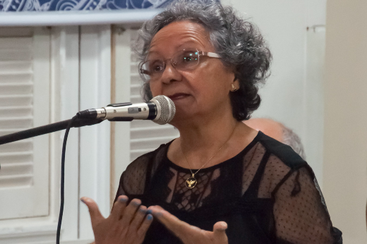 Izaíra Silvino (1945-2021) foi uma referência nas áreas de canto coral, educação musical e cultura no Ceará (Foto: Ribamar Neto / UFC Informa) Imagem: foto da maestrina Izaíra Silvino falando em frente ao microfone
