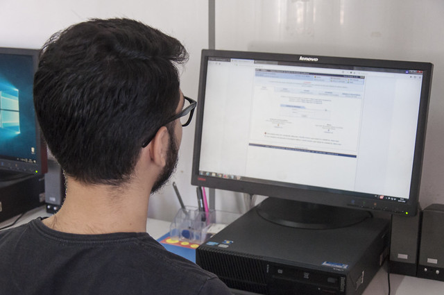 Mudanças tornam mais rígidos os critérios de segurança e determinam a troca periódica de senhas do Sistema Integrado de Informações Institucionais (SI3) (Foto: Victor Braga/UFC) Imagem: Fotografia de uma pessoa de costas utilizando um computador e acessando o SI3 (Foto: Viktor Braga/UFC)
