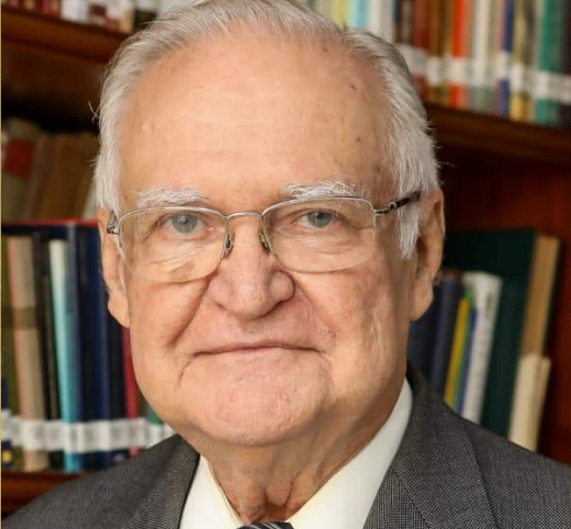 O Prof. Hugo de Brito Machado é considerado um dos maiores nomes do Direito Tributário brasileiro (Imagem: divulgação) Imagem: foto de um senhor branco de cabelos grisalhos de paletó cinza. Ao fundo, há estantes com livros de diversas cores