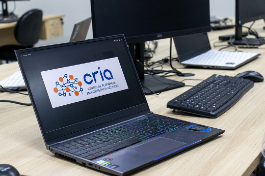 Inaugurado em março deste ano, o CRIA é um espaço da UFC voltado ao desenvolvimento de pesquisas em inteligência artificial, sendo o CEREIA seu projeto inaugural (Foto: Viktor Braga/UFC) Imagem: laptop com imagem da logo do CRIA na tela