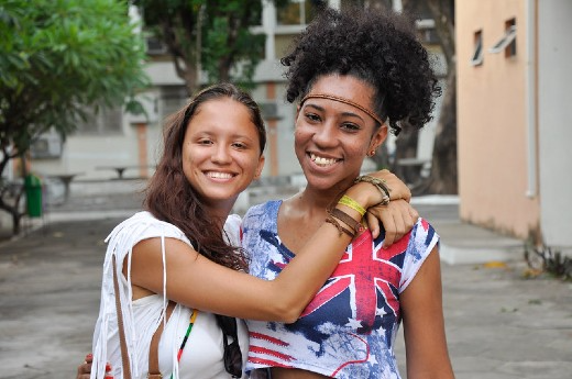 O PAI promove a internacionalização na UFC (Foto: Guilherme Braga/UFC Informa) Imagem: duas mulheres uma negra com blusa colorida e cabelo crespo preso e outra branca com cabelos longos castanho abraçadas