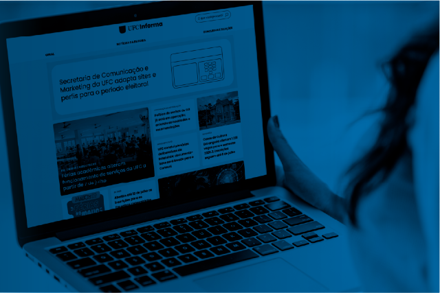 Secretaria de Comunicação e Marketing divulga novos e-mails para contato (Imagem: Secom UFC) Imagem: Fotografia em tons de azul mostra uma pessoa utilizando um notebook sobre o colo. Na tela está aberta a página inicial do portal UFC Informa, com destaques de notícias organizados em blocos. A mão direita da pessoa segura a lateral do computador, enquanto parte do rosto e dos cabelos aparece desfocada à direita da imagem. O teclado do notebook ocupa a metade inferior da fotografia, e o fundo está desfocado, dando destaque ao equipamento e ao portal exibido na tela.